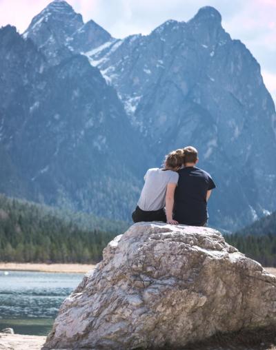 Paar sitzt auf Fels vor einer Berglandschaft